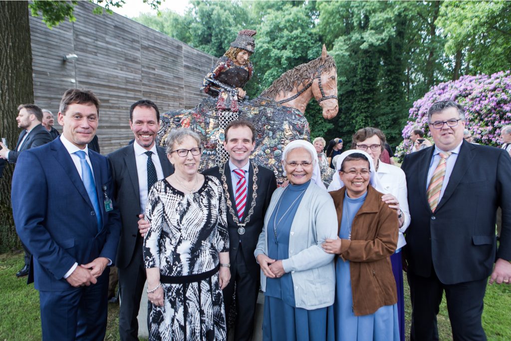 80 jaar Sint Maartenskliniek. V.l.n.r. De heer Van Enk (lid Raad van Bestuur), de heer Van Houdenhoven (voorzitter Raad van Bestuur), Zuster Tine Vink, de heer Slinkman (burgemeester van Groesbeek – Berg en Dal), Zuster Antonie Ardatin, Zuster Wahyu Triningsih, Zuster Annecathrine van Haren, de heer Bruls (burgemeester van Nijmegen). Op de achtergrond het kunstwerk (St Maarten te paard) gemaakt door Carolein Smit t.g.v. het 80-jarig bestaan - 01 juni 2016 Foto: Dennis Vloedmans